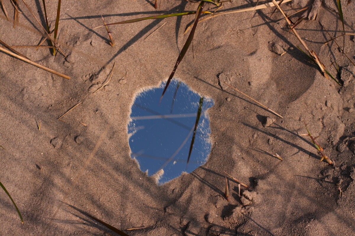 een heldere plas water in het zand